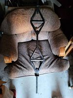 Photo showing the full length of the black metal weight bar with diamond-shaped grip zones, placed on a brown cushioned chair.