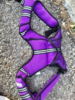 Photo shows a purple neoprene weighted vest with black mesh and white stripes laid on the ground.
