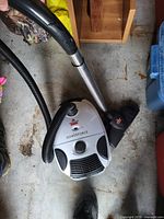 Bissell PowerForce canister vacuum cleaner seen from above on a concrete floor with visible hose and floor wand attachment.