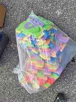 Plastic bag filled with colorful interlocking foam puzzle mats with alphabet letters