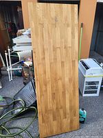 Photo showing a large, heavy wooden board standing vertically with visible natural wood grain and smooth surface.