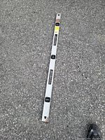 Aluminum spirit level placed on asphalt surface showing its size and condition.