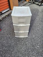 Single stacked 3-drawer plastic storage unit with lid shown outdoors on pavement near a building.