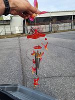 Wind chime held in hand outdoors showing red and orange glass butterfly decorations, metal chimes, and hanging beads.