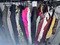 Photo showing the entire rack of assorted women's clothing items hung on hangers including jackets, blazers, sweaters, and tops in various colors and patterns.