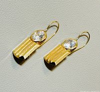 Front view of pair of 10K gold earrings with oval clear gemstones set in vertical ridged gold mountings and hook backs.