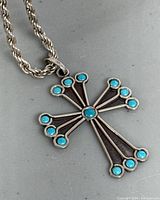 Close-up image of the silver cross pendant with turquoise stone accents, showing design details and condition.