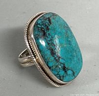 Front side image of a large turquoise and silver ring showing the oval turquoise stone with blue and black matrix and silver twisted rope detail around the bezel.