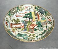 Top view of the shallow bowl showing the colorful hand-painted scene and floral border.