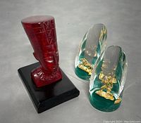 Red Nefertiti bust and two vintage Canadian lucite acrylic paperweights on a gray surface