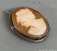 Front view of Victorian cameo brooch pendant showing oval shell cameo with side profile of woman.