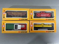 Four COX HO scale mini train cars in original yellow boxes: Robin Hood grain car, Bundy caboose, Gusto pizza boxcar, and Robin Hood tank car, all arranged in a single layer for clear view.
