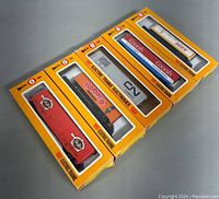 Five COX HO Electric Trains in original yellow boxes, showing front windows with various brand graphics.