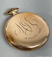 Back of gold pocket watch engraved with initials and August 1925 date.
