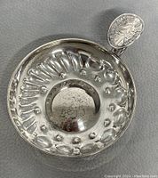 Top view of the sterling silver wine tasting cup showing embossed oval and circular details inside the cup.