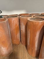 Close-up side views of cylindrical terracotta clay chimney pots grouped together.
