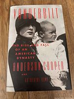 Hard cover book titled 'Vanderbilt: The Rise and Fall of an American Dynasty' by Anderson Cooper and Katherine Howe, with black and white photo cover featuring a woman holding a child.