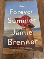 Cover of The Forever Summer by Jamie Brenner, showing a woman with a large red sun hat on a beach.