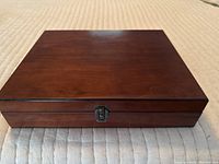 Closed wooden box for essential oils on a light fabric surface, showing wood grain and latch.