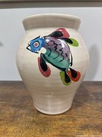 Front view of the cream ceramic pot with colorful fish design.