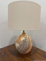 Photo of a Mid-Century Modern style ceramic lamp with marbled brown, tan, and cream glaze on a wooden surface against a white wall.