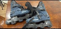 Photo shows a pair of women's size 9 Bauer roller blades, black and navy blue with adjustable straps and four inline wheels.