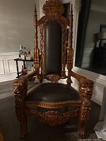 Front view of throne chair showing overall carving and upholstery