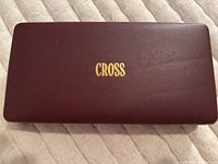 Closed burgundy Cross branded box with gold logo