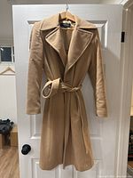 Front view of camel wool coat by Jones New York hanging on door showing overall shape and belt.