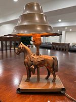 Front view of the vintage lamp showing metal horse figure base and tiered metal lampshade.