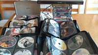 Multiple black DVD storage cases open showing discs in sleeves with printed titles and images.