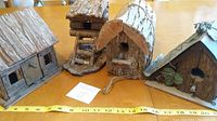 Four handcrafted bark wood bird houses with detailed designs and natural texture arranged on a table.