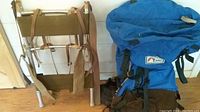 Backpacks shown from front with external frame backpack leaning and blue REI backpack placed beside it.