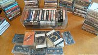 Overview photo showing many cassette tapes stacked and arranged with some inside a storage box.