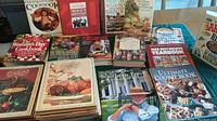 Photo showing a spread of multiple cookbooks including Southern Food by Edna Lewis, Ultimate Cookie Book, and Woman's Day Cookbook among others.