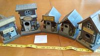 Five vintage mini wooden bird houses arranged in a row on a wooden table with a measuring tape showing size.