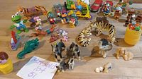 Wide view showing a variety of miniature toys and animal figurines including dogs, a tiger, a green frog, and small vehicles like a truck and a car.