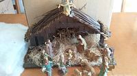 Front view of vintage nativity set with manger stable and most figures arranged inside and nearby