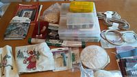 Wide view of tote contents showing embroidery tools, thread organizers, fabric pieces, and craft books arranged on a table.