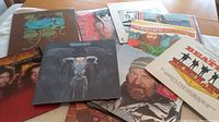 Overview photo showing a collection of 15 vinyl record albums stacked and spread on a table, featuring identifiable covers from The Beatles, Beach Boys and Yes.