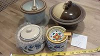 Photo showing all four ceramic and stoneware containers with one honey pot containing wooden dipper, measuring tape for scale