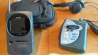 Photo showing Casio TV-480 LED Pocket Color Television with Sony Walkman cassette player and headphones on a wooden table