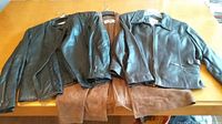 Three women's jackets laid on a wooden surface: black leather jacket on the left, brown suede jacket in the middle, and brown leather jacket on the right, showing overall condition and styles.