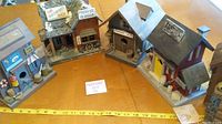 Five wood bird houses arranged in a village layout, showing different building styles and painted details including signage and roof shingles.