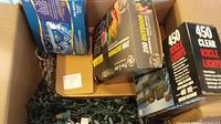 Box with multiple sets of Christmas lights, including boxes labeled 200 Outdoor Lights and 450 Clear Icicle Lights with green light strands inside.