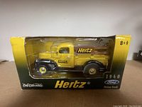 Yellow and black 1940 Ford pickup truck diecast model in original packaging with Hertz branding visible on truck and box.