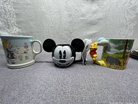 Front view of three Walt Disney ceramic mugs: Alice in Wonderland, 3D Mickey Mouse, and Winnie the Pooh with Pooh handle.