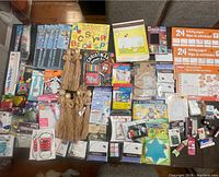 Overview of various crafting supplies laid out on table including yarn tassels, paint, scissors, educational paper pads, and Christmas themed crafting booklet.