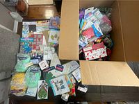 Wide view of table with assorted craft supplies spread out, including pastel chalks, paint kits, stencils, gift wrapping kits, and other accessories.
