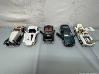 Five die-cast cars displayed side by side showing various colors and opened parts illustrating model features and condition.
